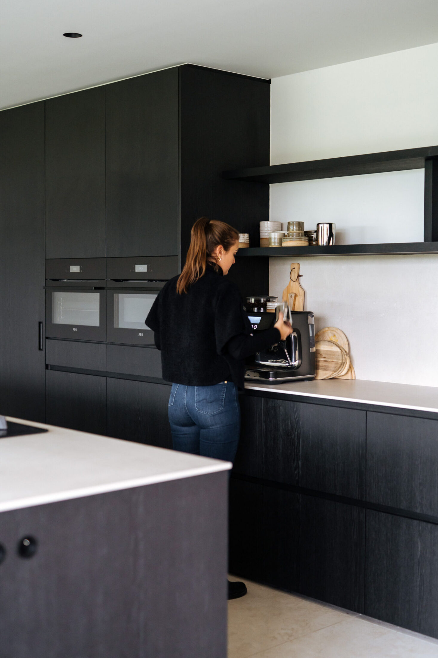 Moderne keuken met zwarte kasten, ingebouwde ovens en open wandrekken in Moorsele, Kaster Keukens