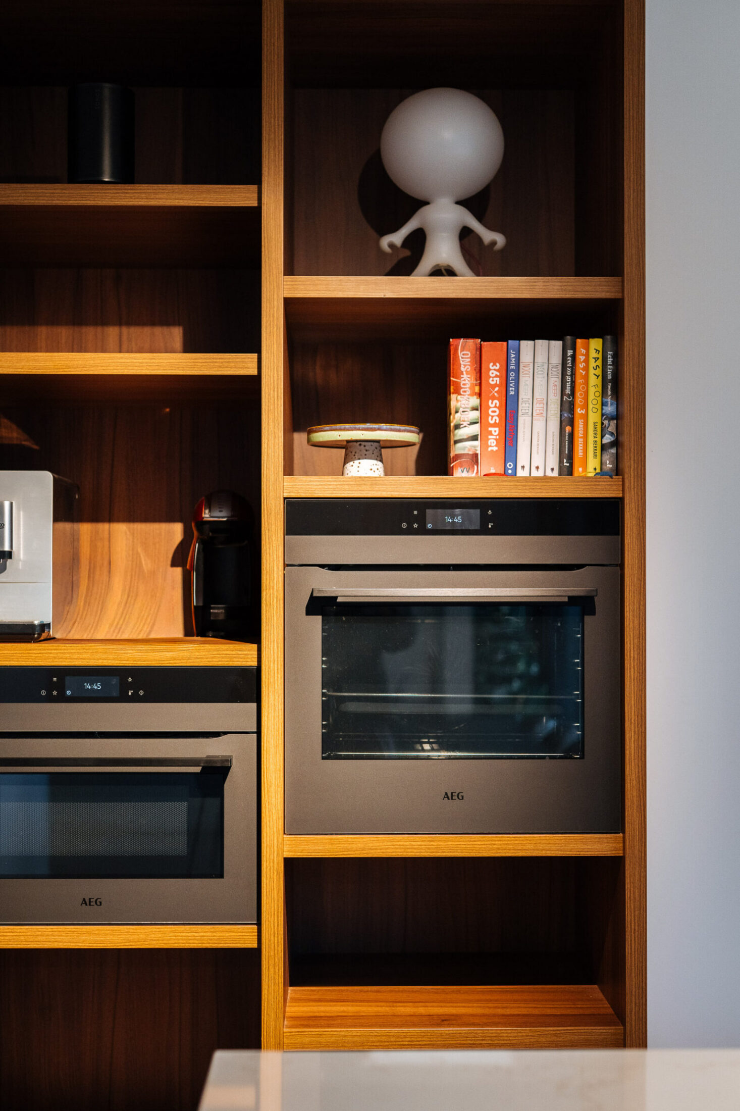 Detail van een moderne keuken met houten open kast rond ingebouwde ovens in Drongen, Kaster Keukens
