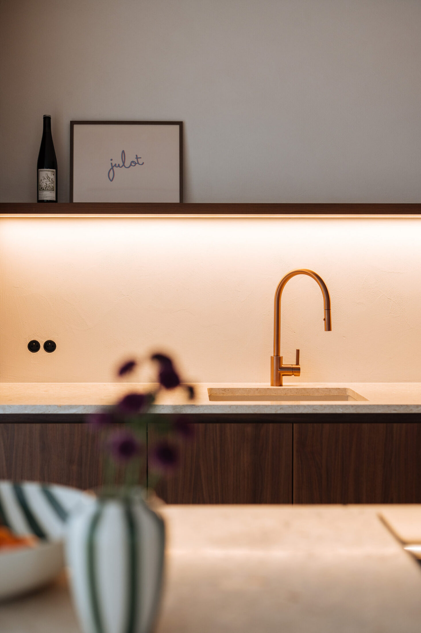 Detail van een moderne keuken met goudkleurige kraan en verlichte achterwand in Zwevegem, Kaster Keukens
