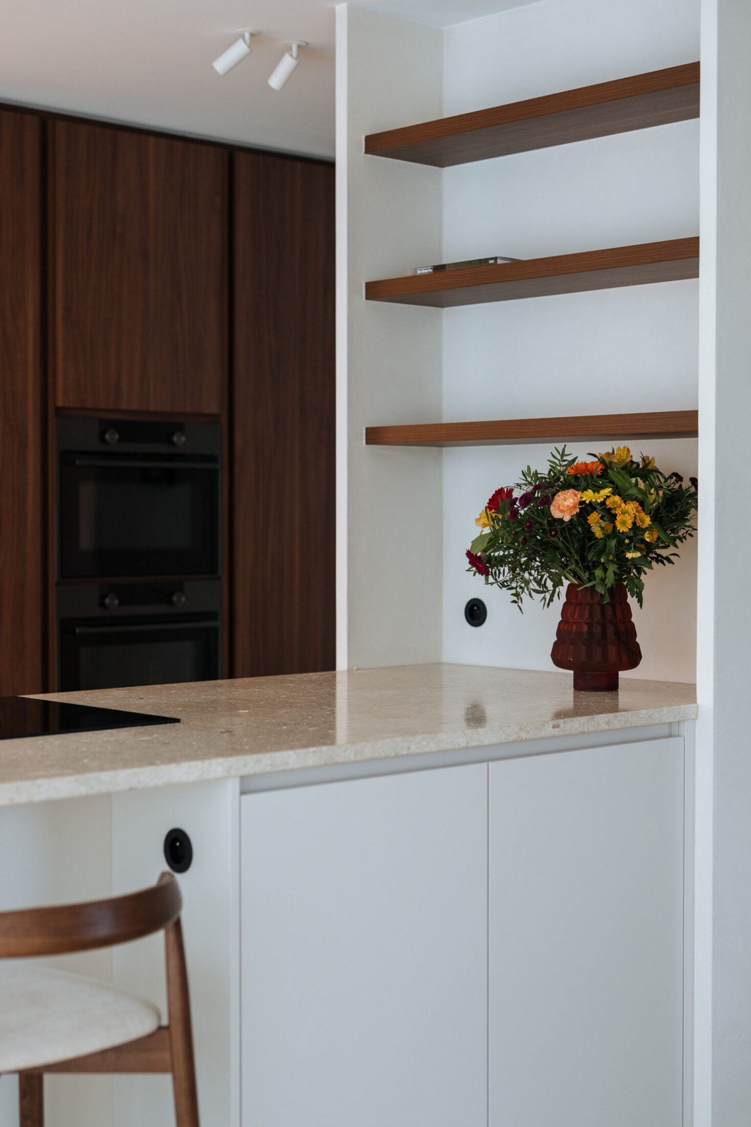 Detail van een moderne keuken met witte fronten, open wandplanken en notelaar hoge kasten in Zwevegem, Kaster Keukens