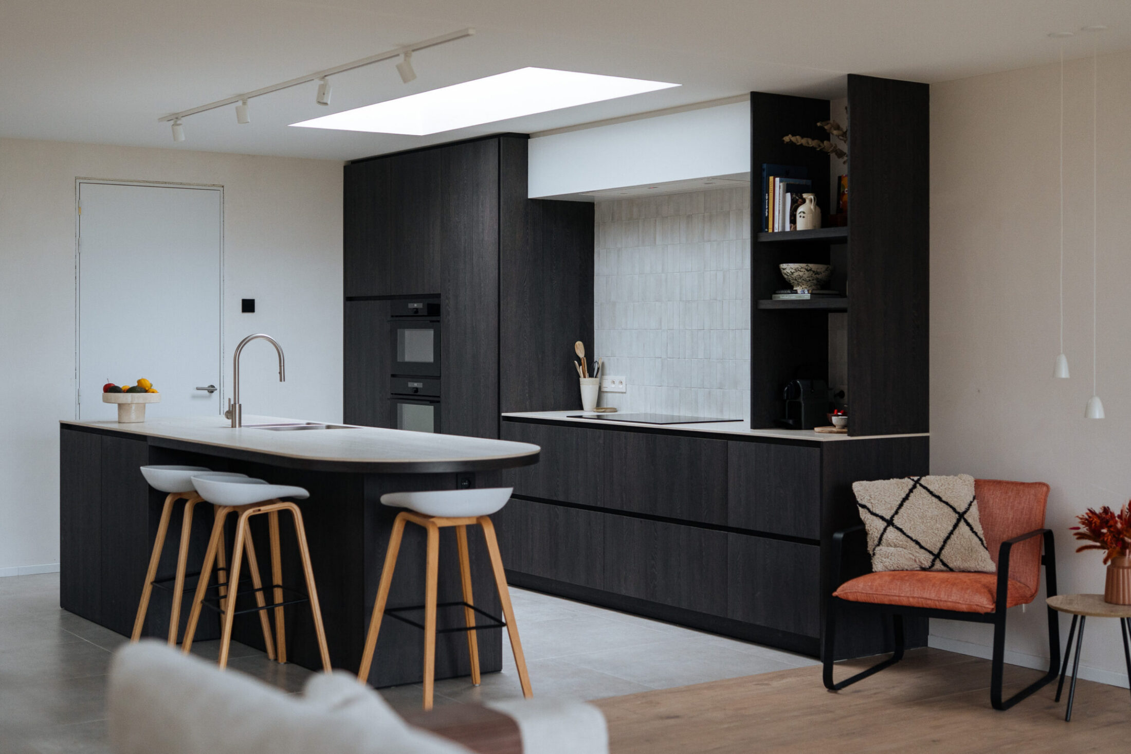 Moderne keuken met donker kookeiland, houten barkrukken en zwarte hoge kasten met open rek in Ardooie, Kaster Keukens
