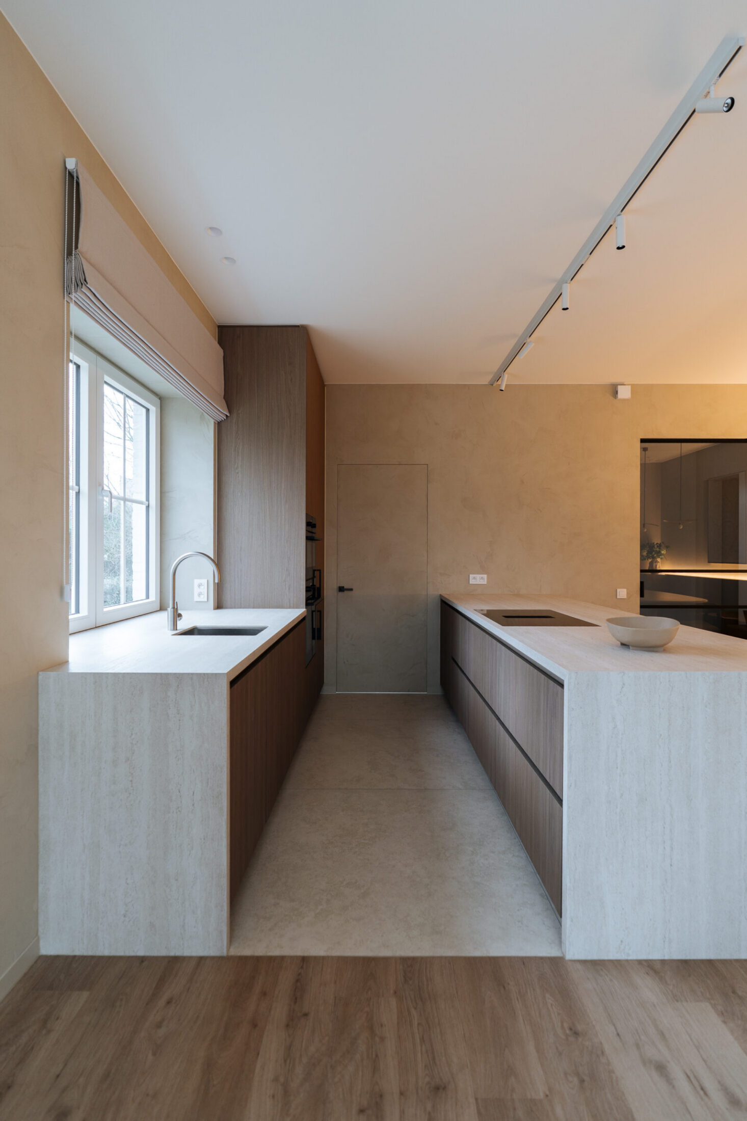 Moderne keuken met twee lichte keukenblokken, notelaar kasten en houten vloer in Oostduinkerke, Kaster Keukens