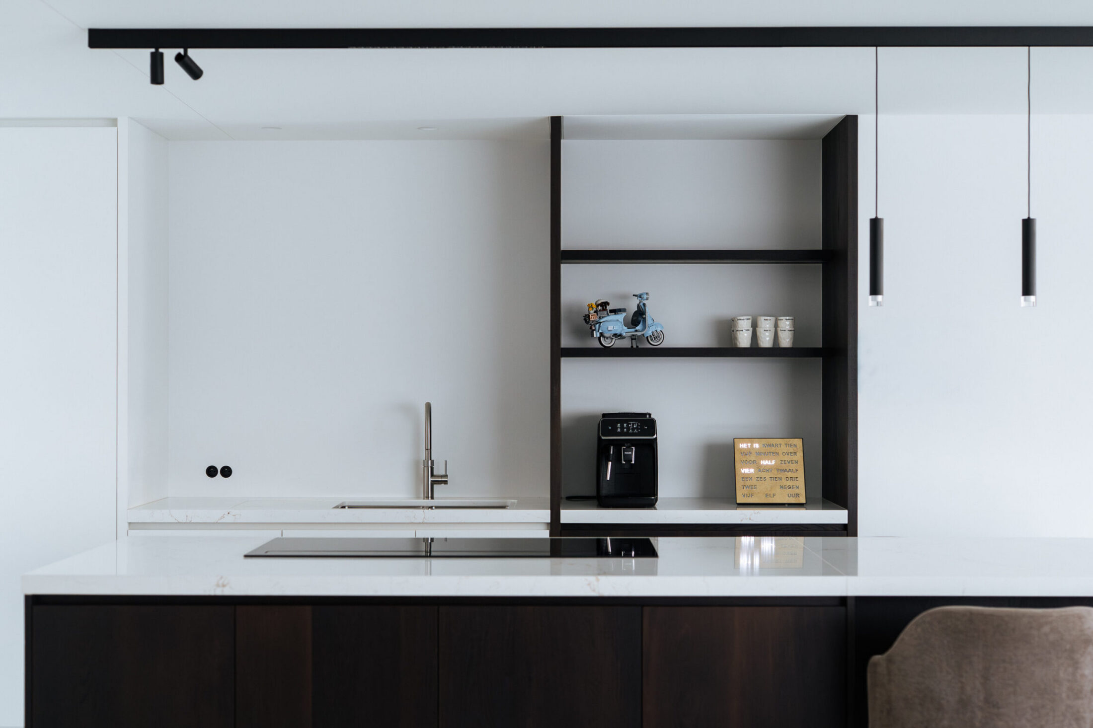 Moderne keuken met witte kastenwand, zwart open rek en kookplaat in het eiland in Oostnieuwkerke, Kaster Keukens