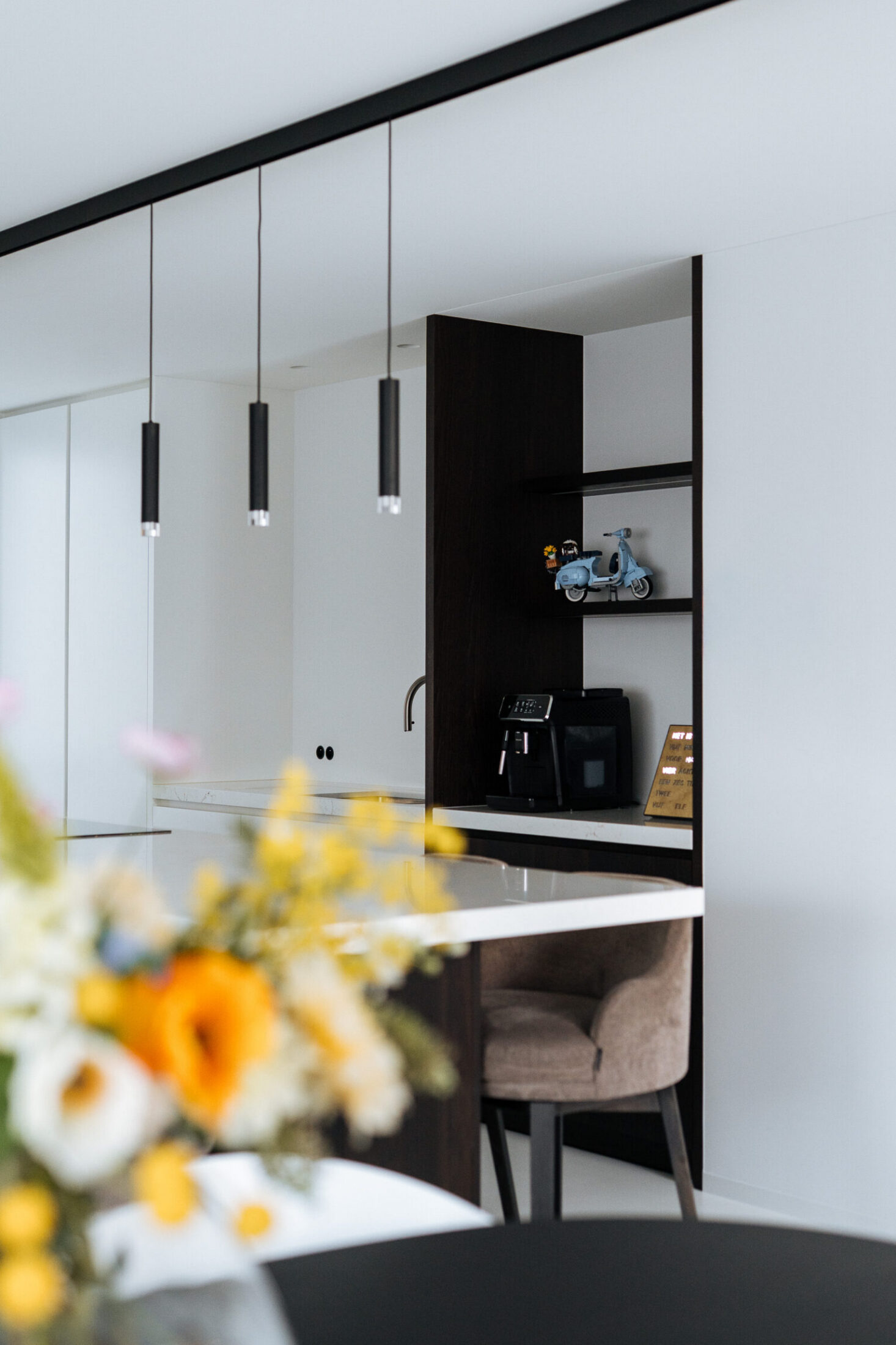 Detail van een moderne keuken met zwarte hanglampen en open rek boven het werkblad in Oostnieuwkerke, Kaster Keukens