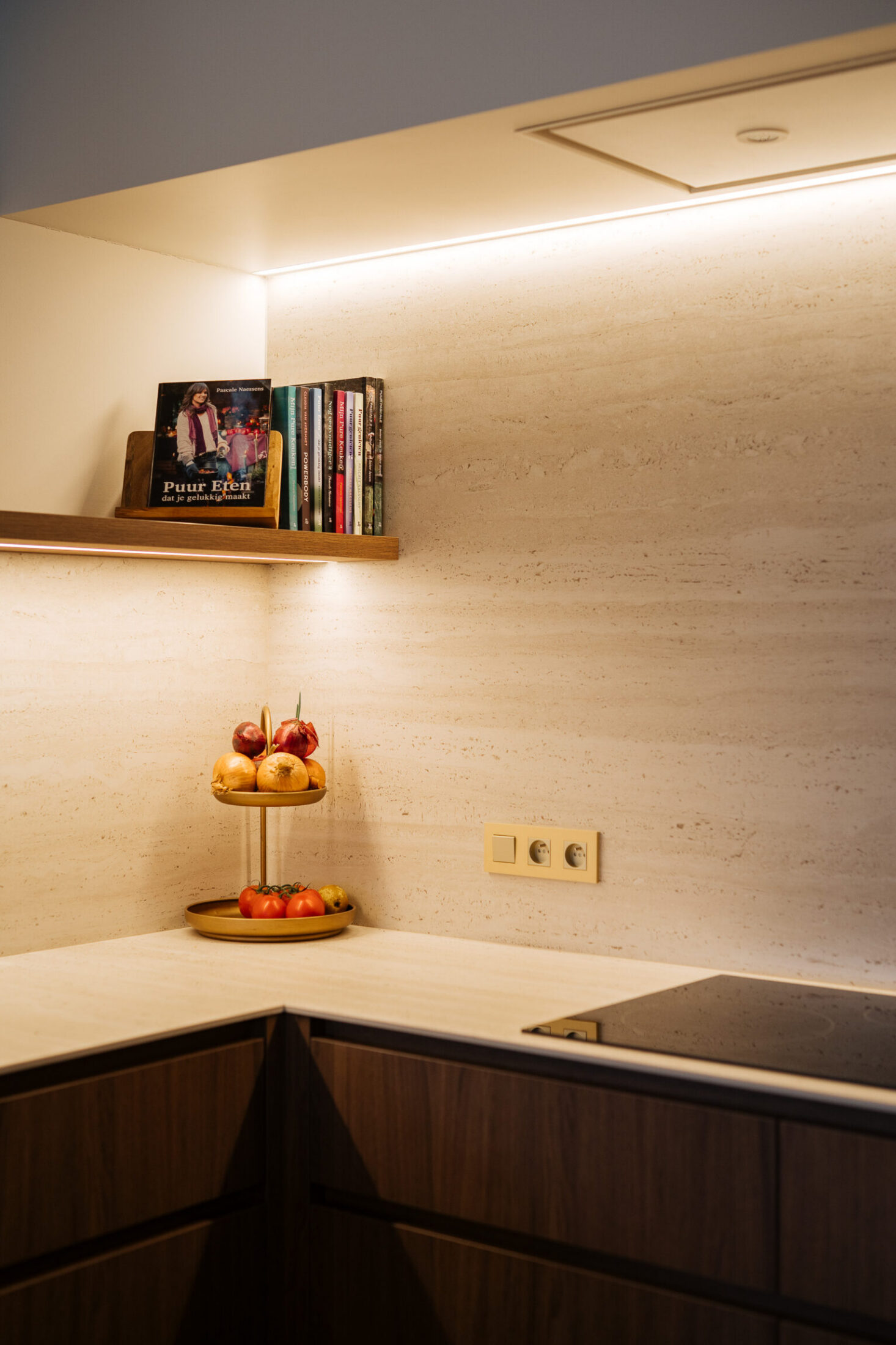 Detail van een moderne keuken met houten wandplank, ledverlichting en kookplaat in de hoek in Roeselare, Kaster Keukens