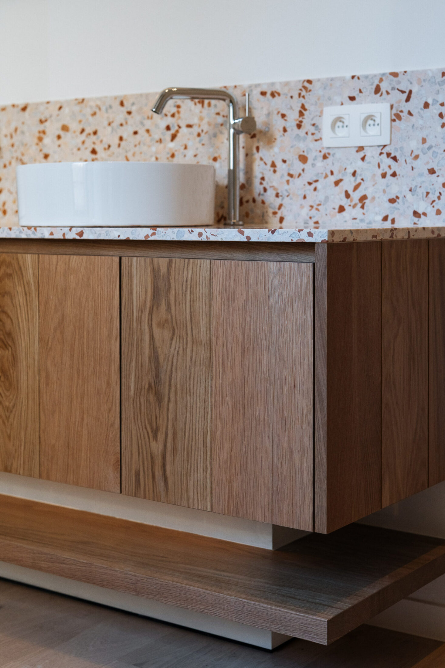 Detail van een zwevend badkamermeubel op maat in eiken met terrazzo blad en waskom in Kortrijk, Kaster Keukens