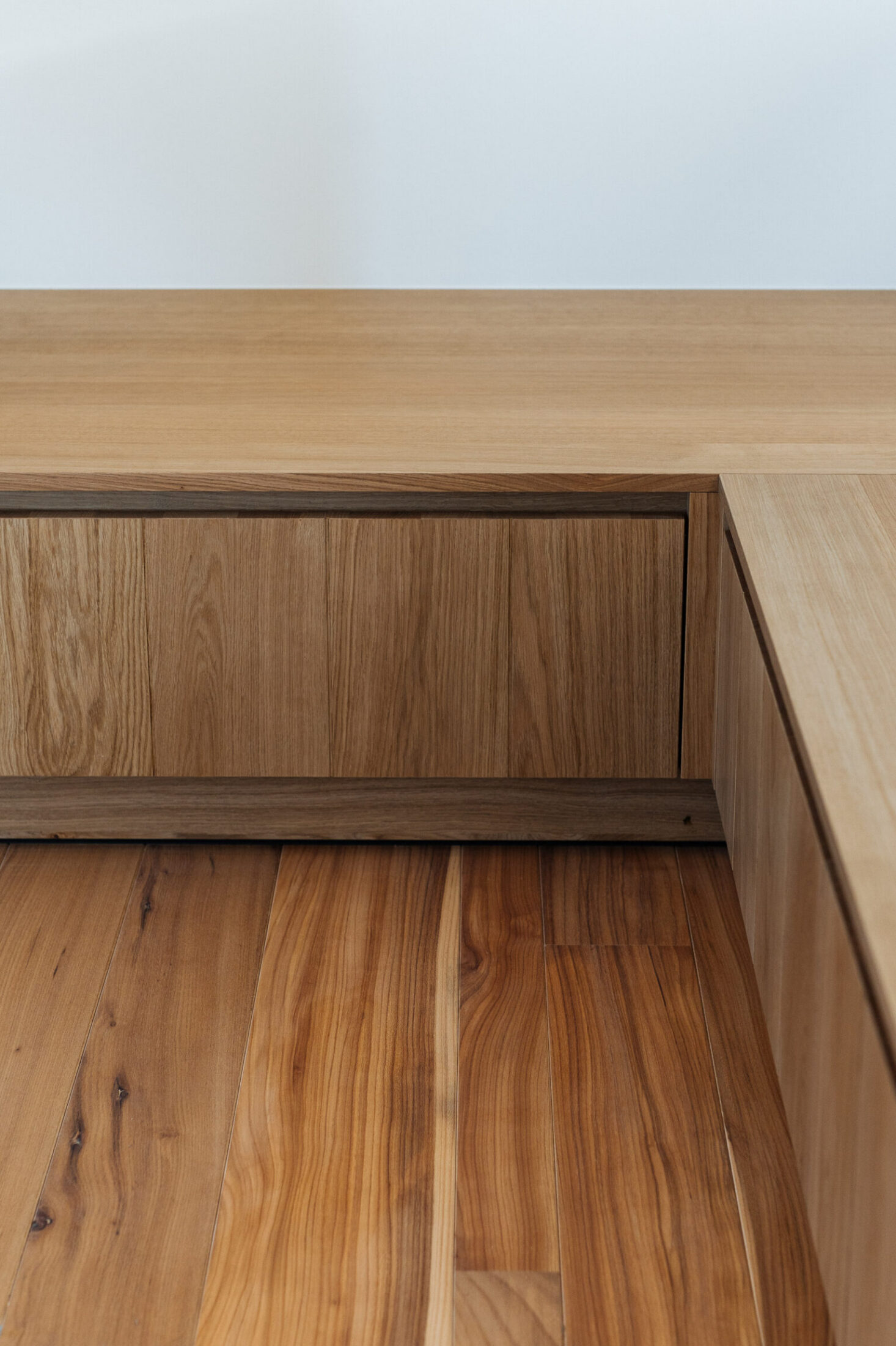 Detail van een eiken zitbank op maat in de hoek op een houten vloer in Kortrijk, Kaster Keukens