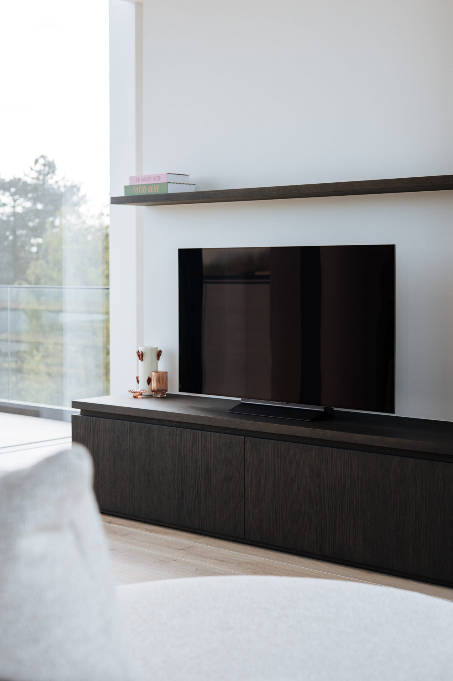 Detail van een tv-meubel op maat met donkere lage kast en zwevend rek boven de tv in Lendelede, Kaster Keukens
