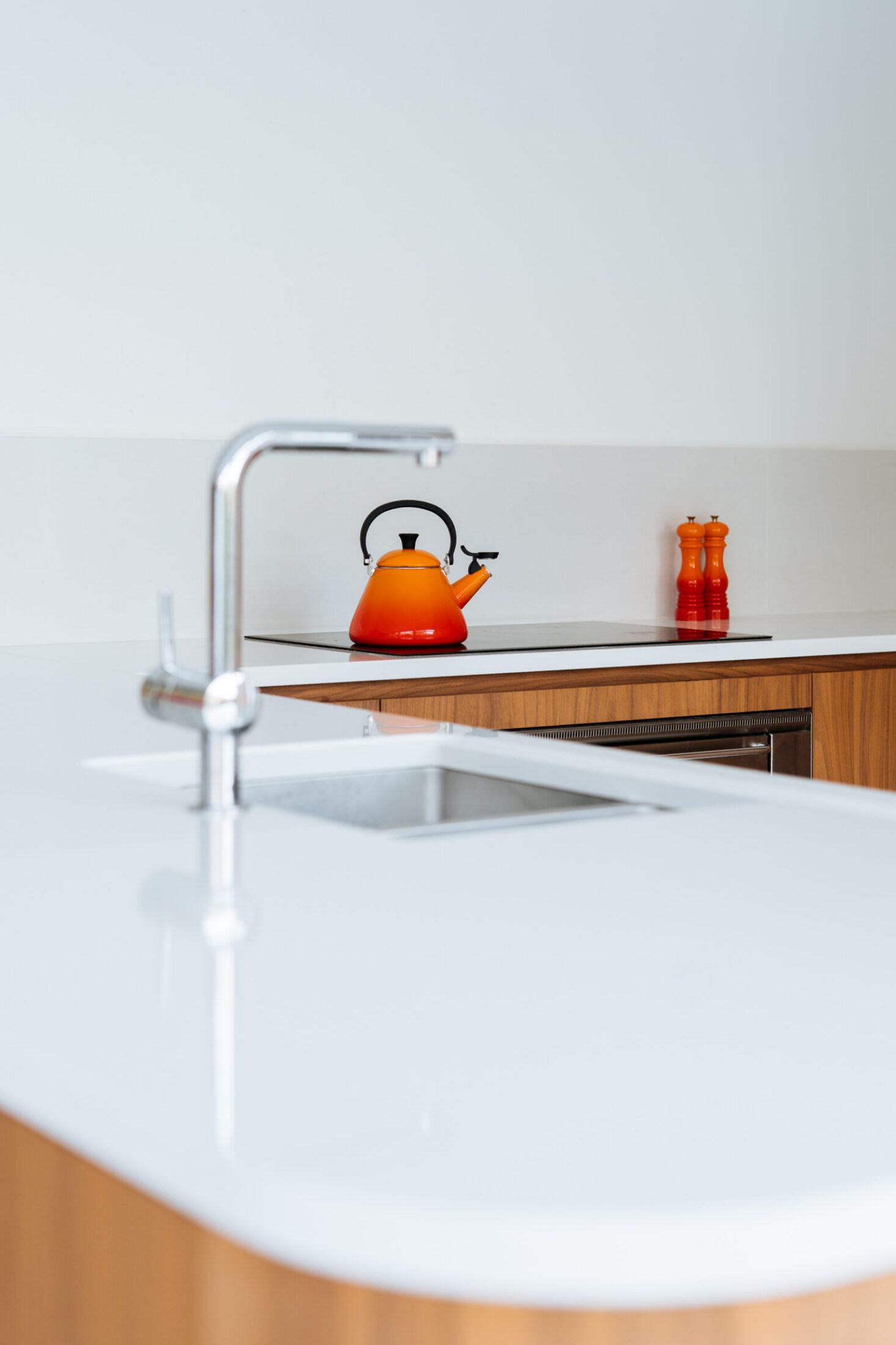 Detail van een moderne keuken met afgerond wit werkblad, inox kraan en spoelbak in Kortrijk, Kaster Keukens