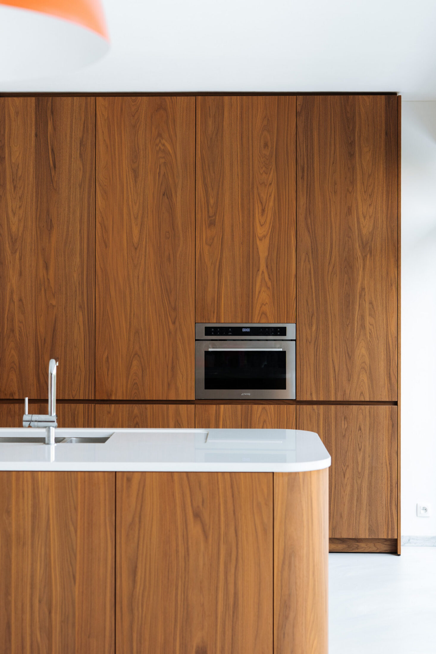 Moderne keuken met houten hoge kasten, inbouwoven en afgerond eiland met wit werkblad in Kortrijk, Kaster Keukens