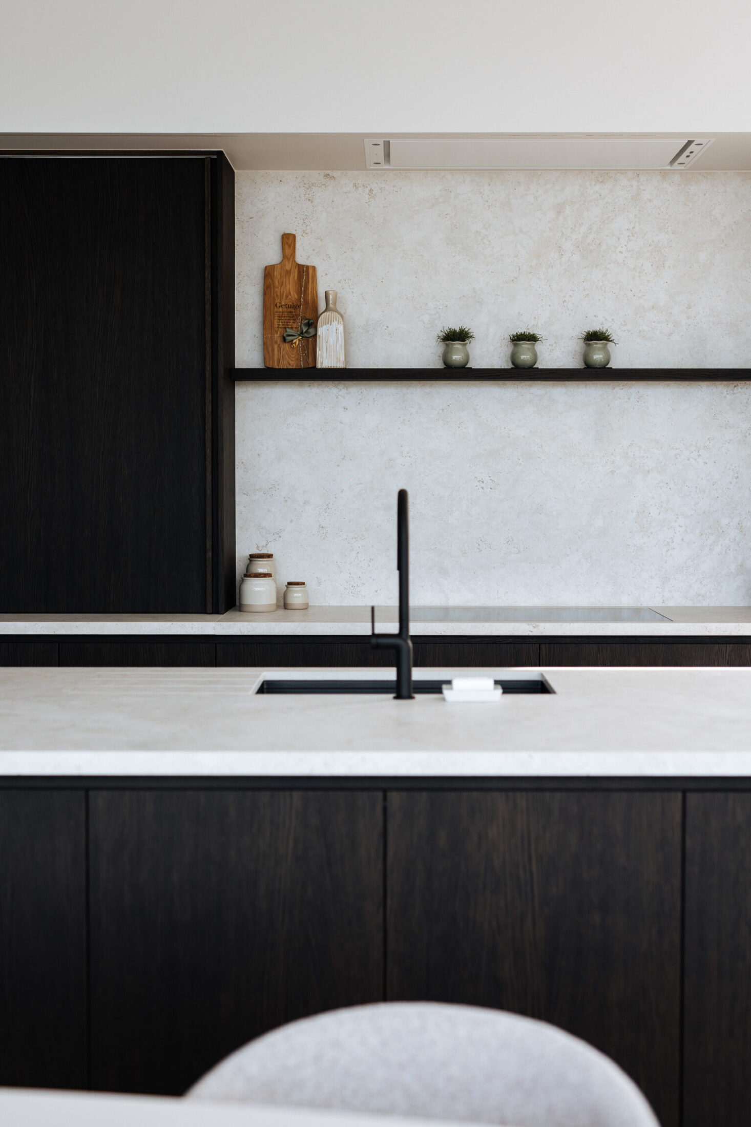 Detail van een moderne keuken met zwarte kraan, wit werkblad en zwart wandrek in Lendelede, Kaster Keukens