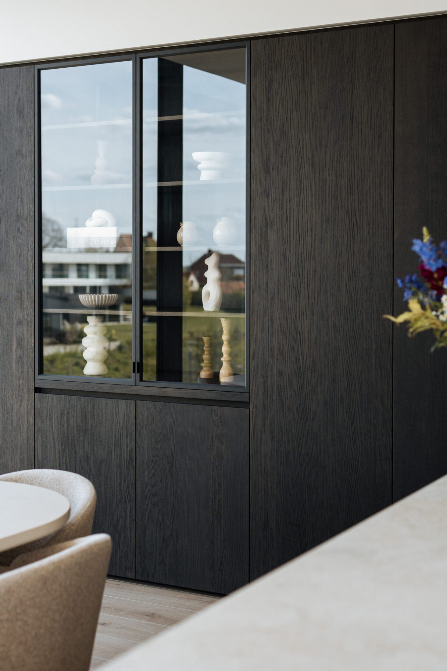 Detail van een moderne keuken met donkere kastenwand en glazen vitrinekast in Lendelede, Kaster Keukens