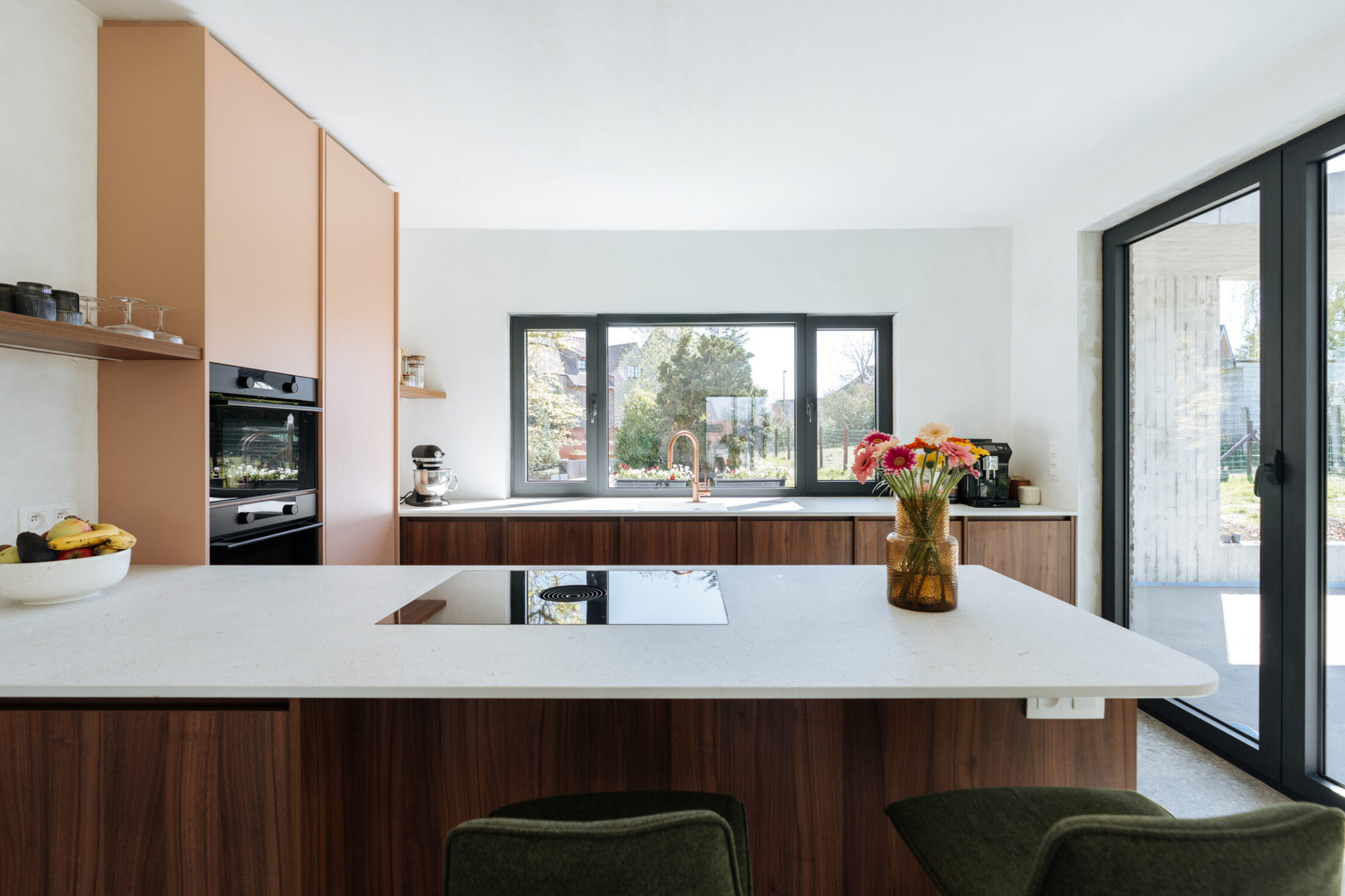 Moderne keuken met notelaar onderkasten, wit kookeiland en roze hoge kasten in Oosterzele, Kaster Keukens
