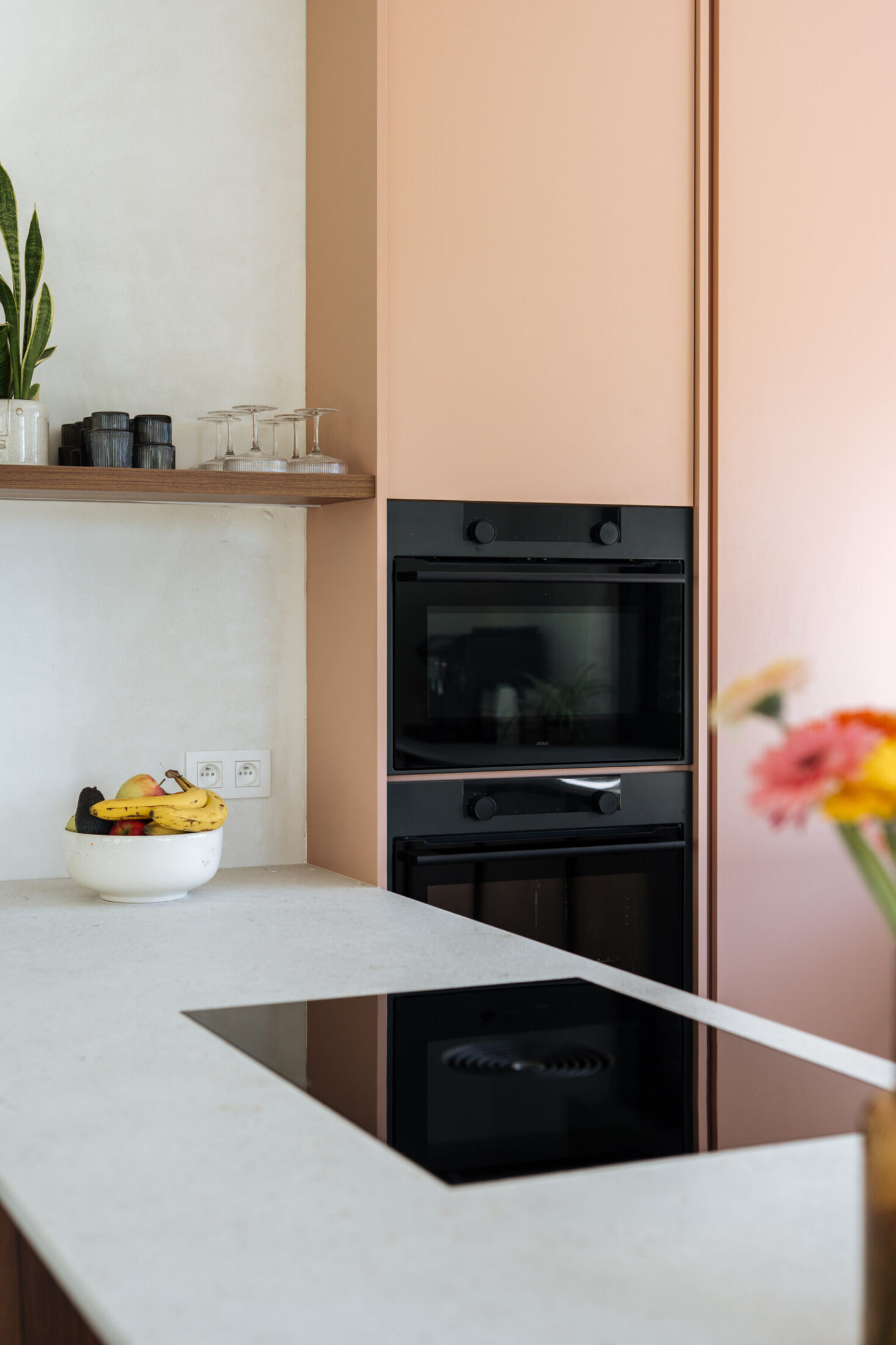 Detail van een moderne keuken met roze hoge kasten, inbouwovens en wit werkblad in Oosterzele, Kaster Keukens