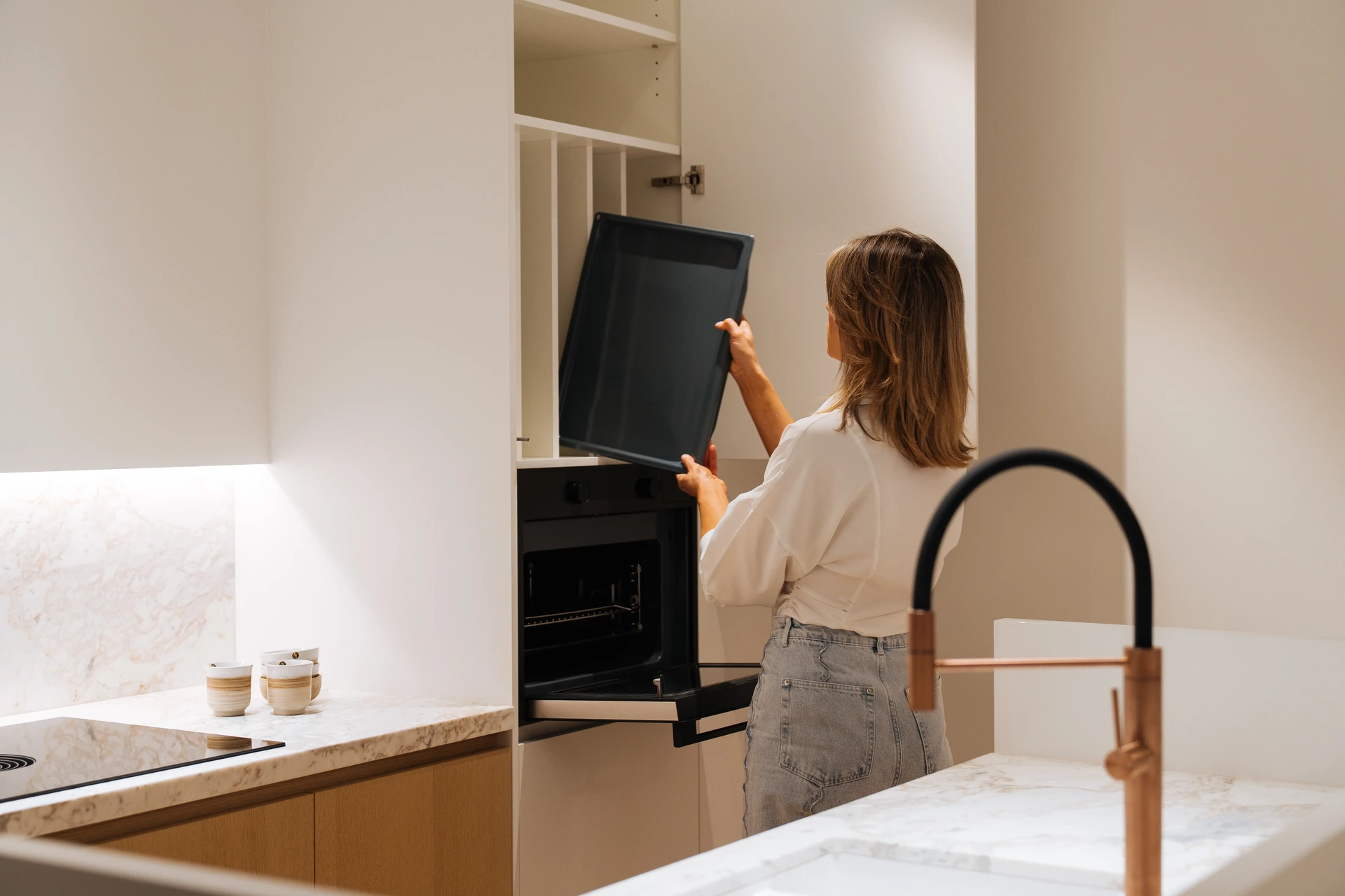 Hoge kast met ingebouwde oven en indeelvakken erboven, afwerking en binnenwerk van een keuken op maat