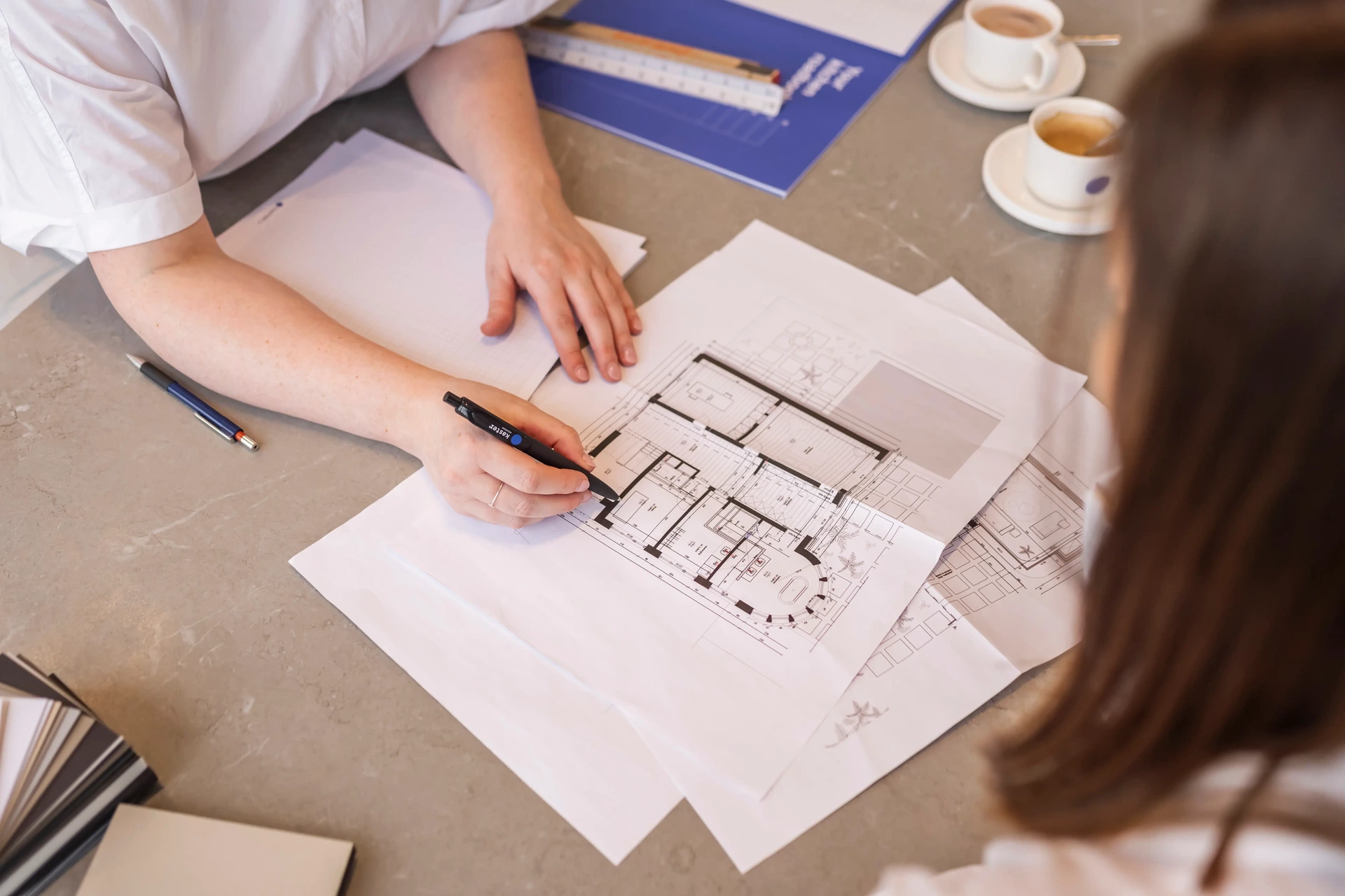 Interieurarchitect schetst een keukenontwerp op het grondplan tijdens een bezoek aan de toonzaal in Roeselare