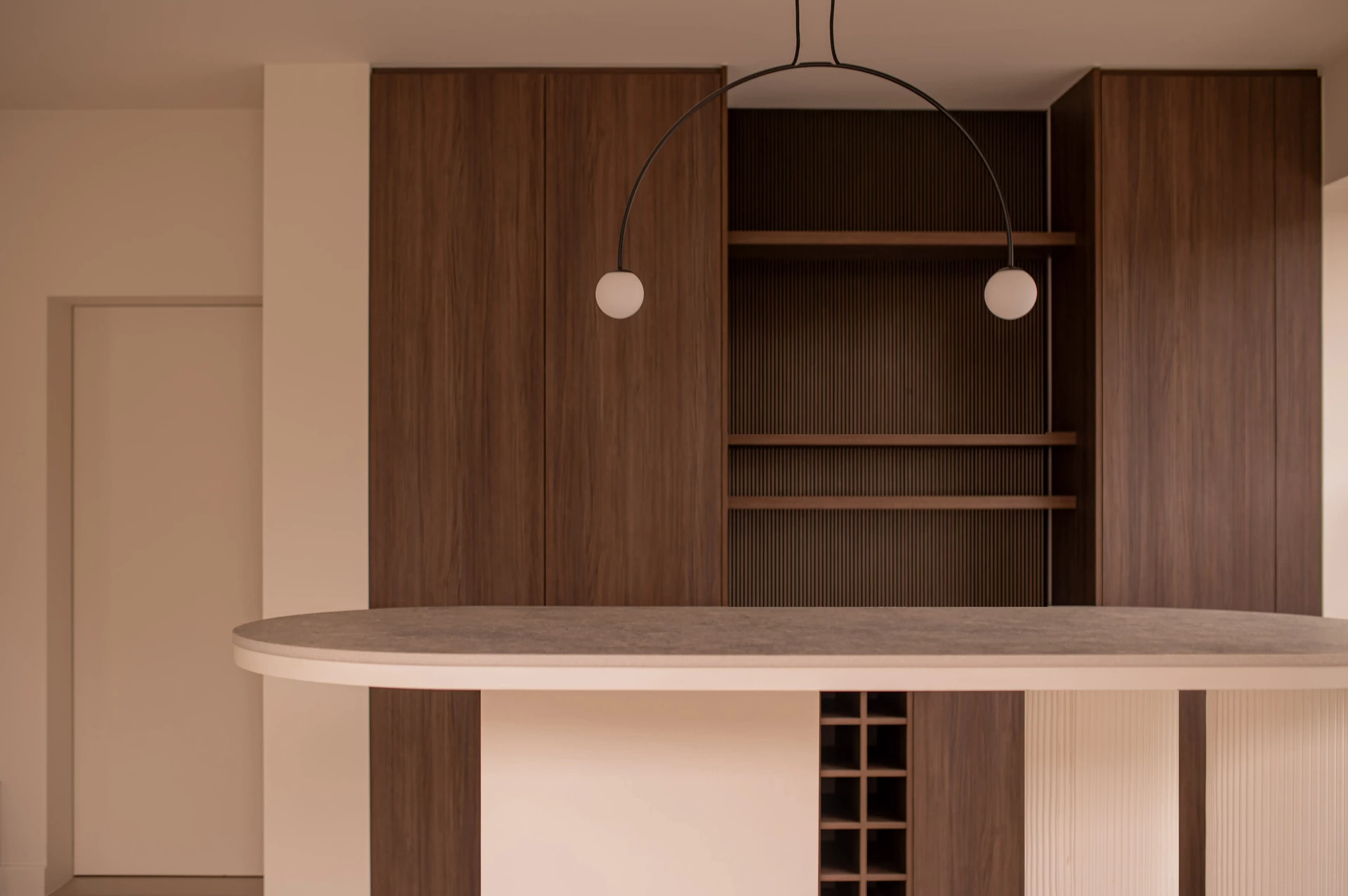 Kastenwand in notelaar met ronde bar en open vakken, maatwerk in dezelfde stijl als de keuken