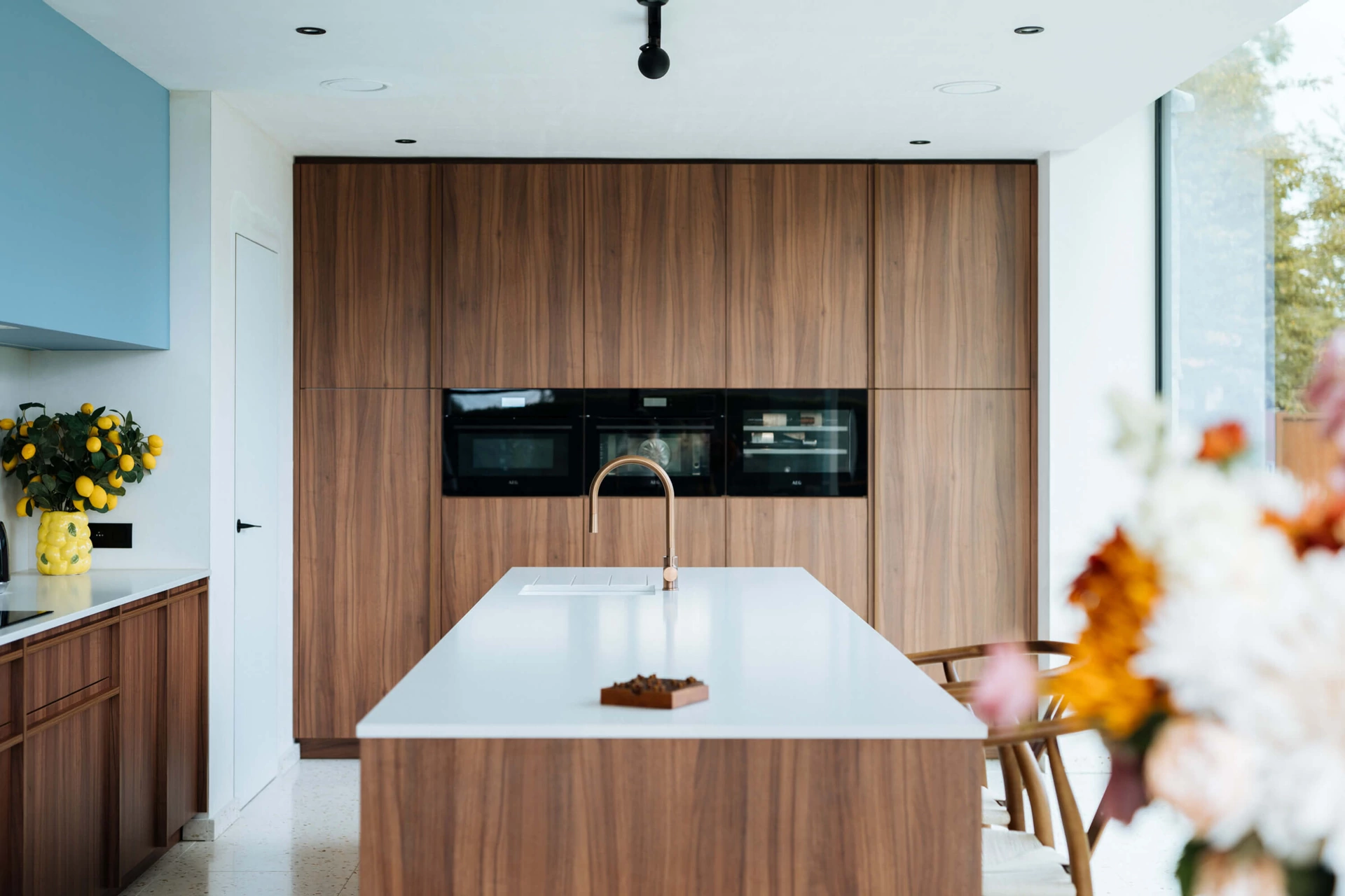 Keuken op maat met hoge kastenwand in notelaar en wit eiland, voor de regio Waregem