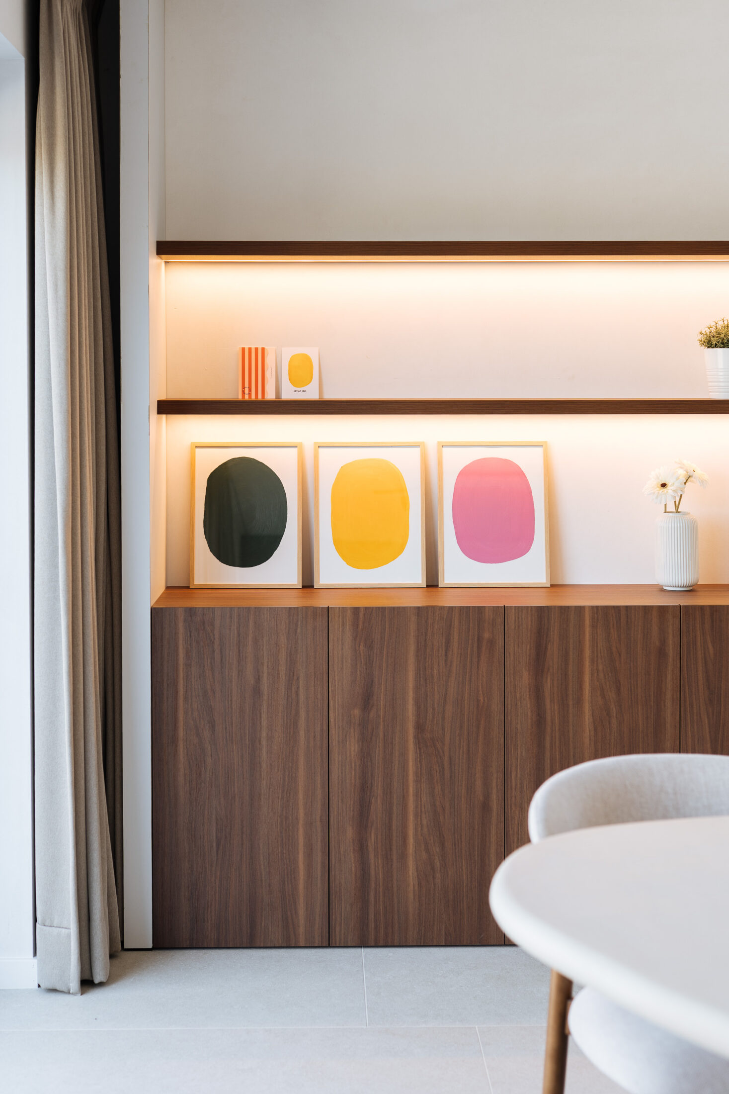 Detail van een wandkast op maat met verlichte open rekken boven een notelaar kast in Aalter, Kaster Keukens