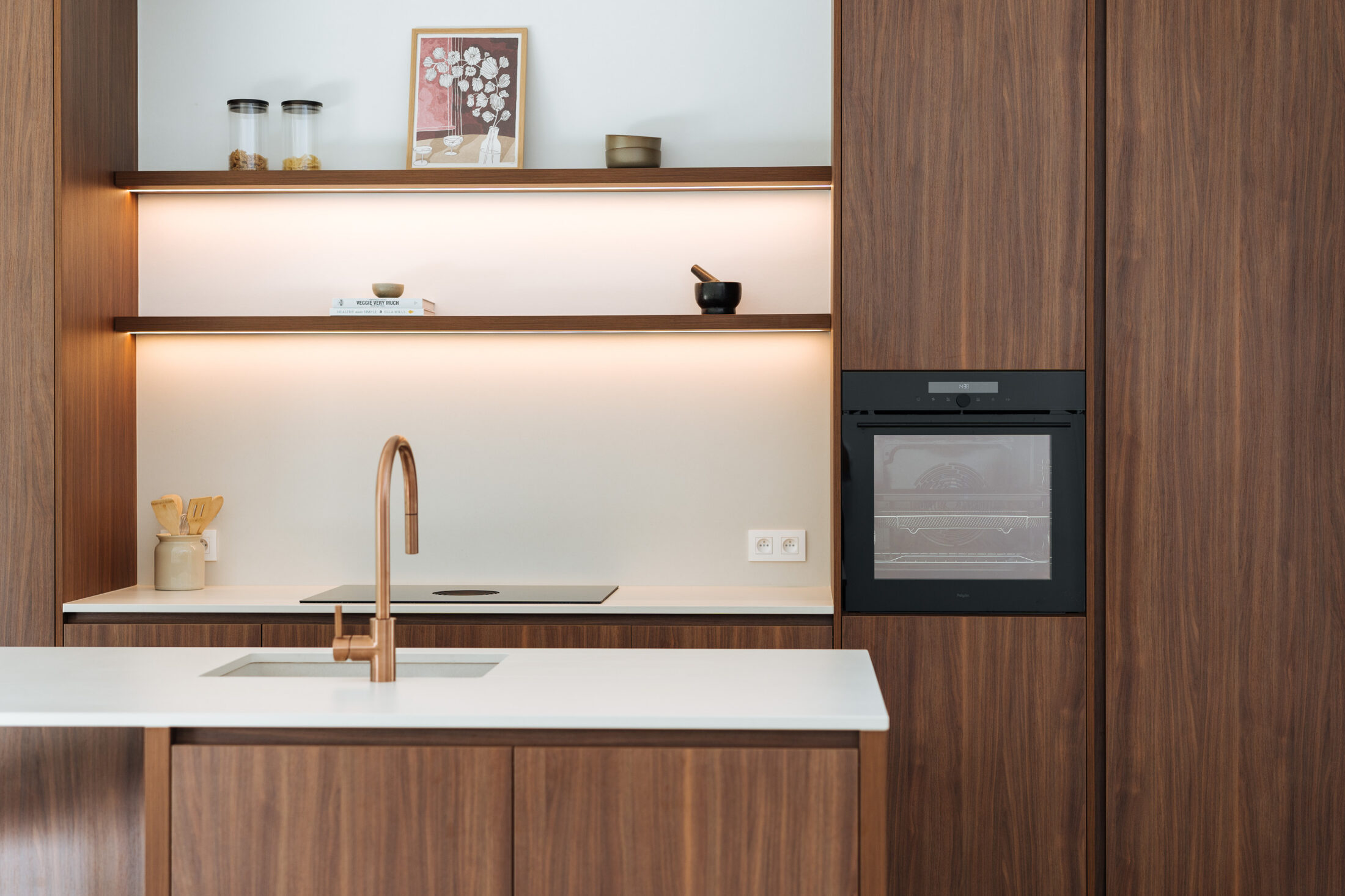 Moderne keuken met notelaar kastenwand, verlichte open rekken, inbouwoven en koperen kraan in Kortrijk, Kaster Keukens