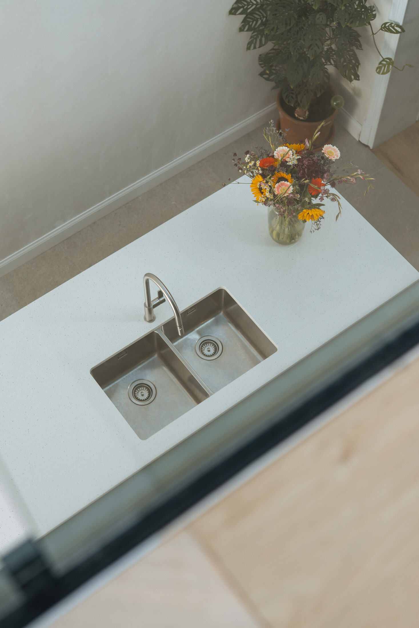 Moderne keuken met donkergroene fronten, wit werkblad, lang kookeiland met zitplaatsen en een open koffienis, Kaster Keukens.