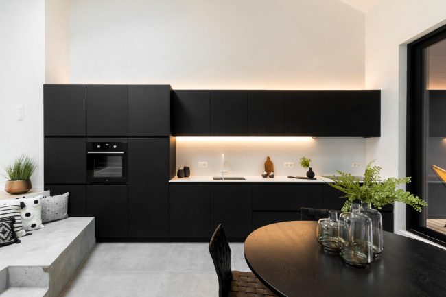 Industriële keuken met zwarte fronten, wit werkblad en ledverlichting in Gent, Kaster Keukens