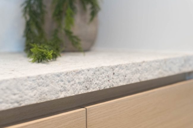 Detail van een landelijke keuken met eiken fronten en lichtgrijs natuursteen werkblad in Knokke, Kaster Keukens