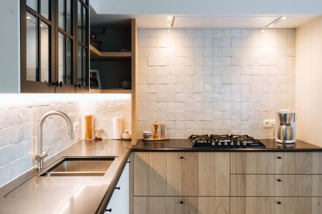 Landelijke keuken met eiken onderkasten, zwart werkblad, gaskookplaat en witte wandtegels in Veurne, Kaster Keukens