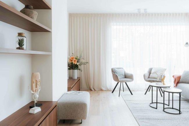 Kastenwand op maat in notelaar met open rekken en lage kast in een lichte living in Kortrijk, Kaster Keukens