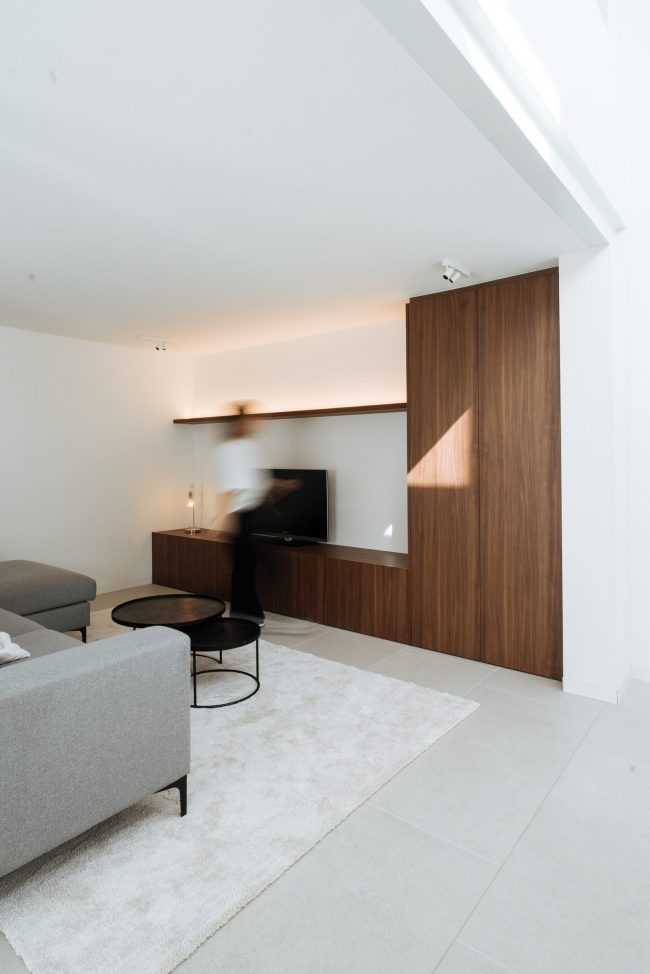 Tv-meubel op maat in notelaar in een lichte leefruimte met grijze zetel in Kortrijk, Kaster Keukens