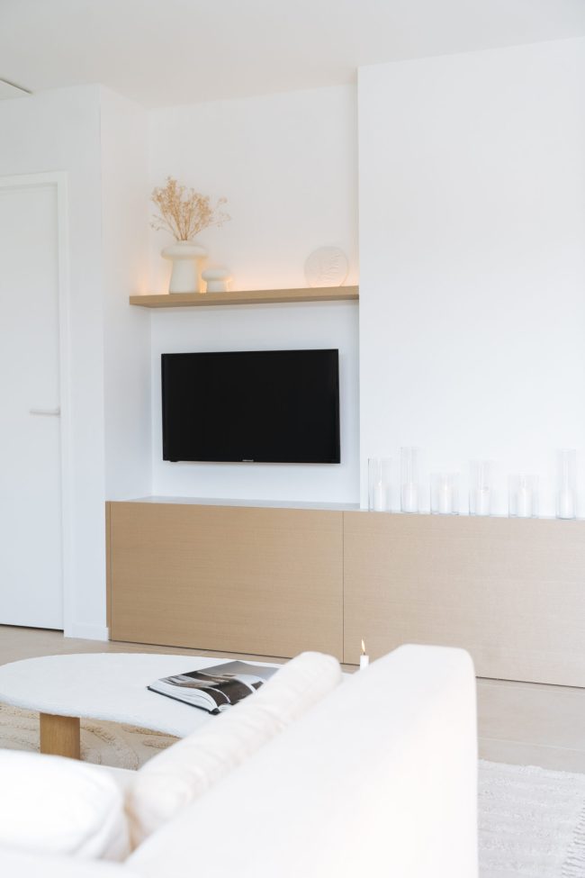 Tv-meubel op maat met eiken onderkast en verlichte wandplank in de leefruimte in Middelkerke, Kaster Keukens