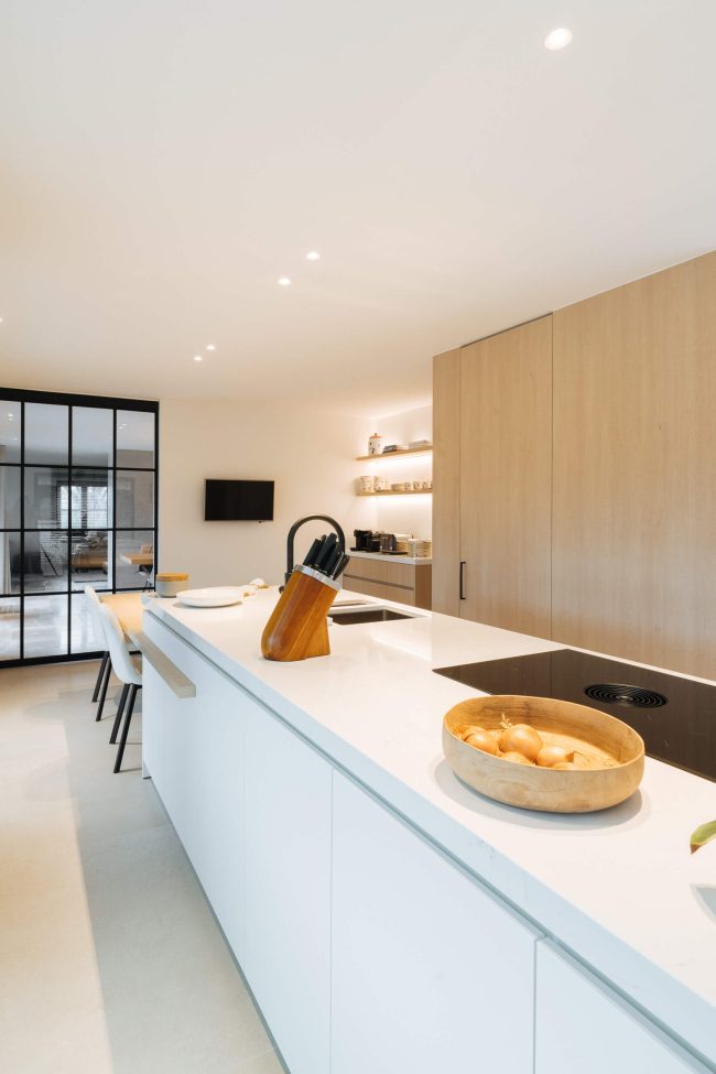 Moderne keuken met lang wit eiland en lichte eiken kastenwand in Bellegem, Kaster Keukens