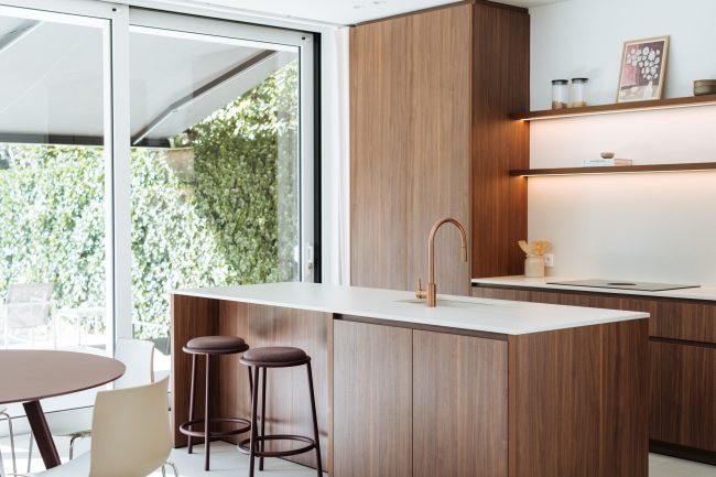 Moderne keuken met notelaar fronten, wit werkblad, koperen kraan en bordeaux barkrukken in Kortrijk, Kaster Keukens