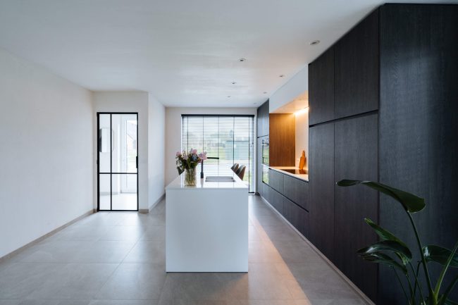 Moderne keuken met zwarte houten kastenwand en wit kookeiland in Meulebeke, Kaster Keukens