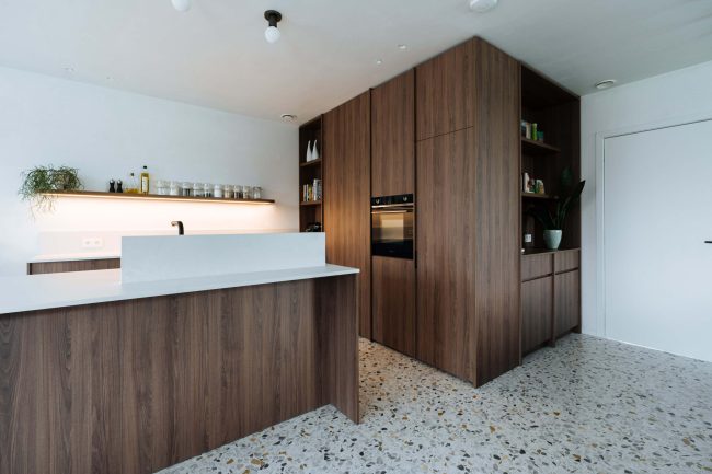 Moderne keuken met donkere houten fronten, wit werkblad en terrazzovloer in Roeselare, Kaster Keukens
