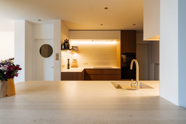 Moderne keuken met kookeiland, koperkleurige kraan en verlichte achterwand in Roeselare, Kaster Keukens