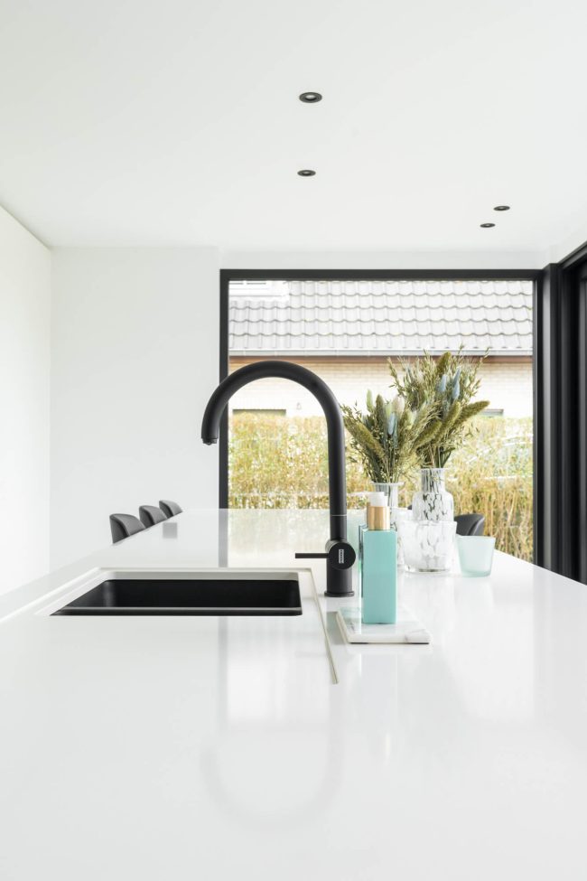 Scandinavische keuken met wit werkblad, zwarte spoelbak en zwarte kraan in Gistel, Kaster Keukens
